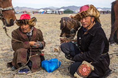 OLGIY, MONGOLIA - SEP 30, 2017: Eagle Hunters at traditional clothing, with a golden eagle on his arm during annual national competition with birds of prey 