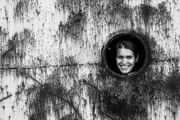 さびた鉄の壁に丸い窓の若い女性の肖像画 モノクロ写真 — ストック写真