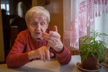 Duygusal olarak masada oturan yaşlı bir kadın konuşuyor.