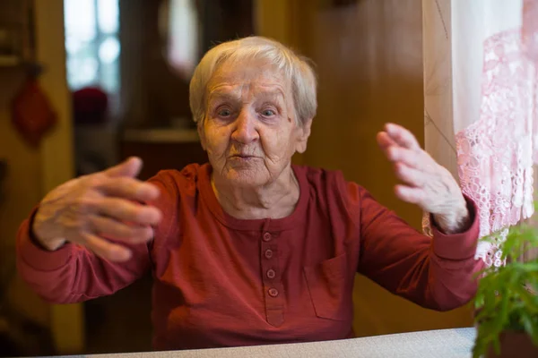 Пожилая Женщина Говорит Эмоционально Сидя Столом — стоковое фото