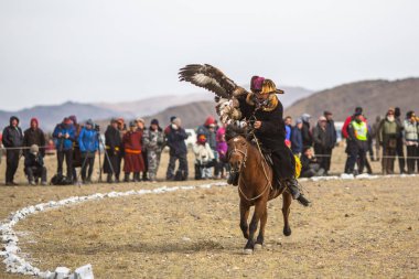 Olgiy, Moğolistan - Eyl 30, 2017: Kartal avcı kuşları Berkutchi Batı Moğolistan ile yıllık Ulusal yarışma sırasında kolunda altın kartal ile geleneksel kıyafetleri.