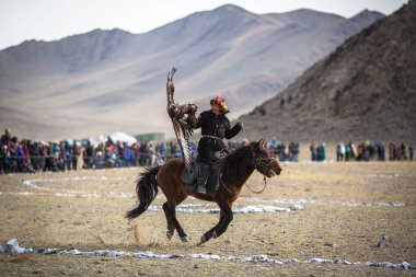 Olgiy, Moğolistan - Eyl 30, 2017: Kartal avcı kuşları Berkutchi Batı Moğolistan ile yıllık Ulusal yarışma sırasında kolunda altın kartal ile geleneksel kıyafetleri.
