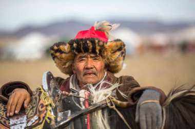 Olgiy, Moğolistan - Eyl 30, 2017: Kartal avcı kuşları Berkutchi Batı Moğolistan ile yıllık Ulusal yarışma sırasında kolunda altın kartal ile geleneksel kıyafetleri.