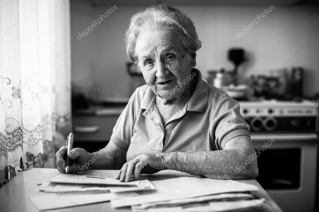 elderly woman fills the bill for payment of utility services.