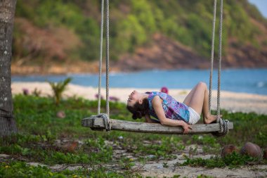 Deniz plaj ahşap salıncağa genç karışık ırk kadın.