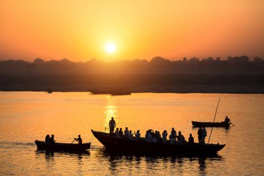 Ganj nehrinde tekne ile Hacı siluetleri ile şafak. Varanasi, Hindistan.