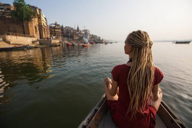 Varanasi, Hindistan ve kıyı Ganj nehrinde su üzerinden dreadlocks bir teknede genç kadın Gezgin kayar.