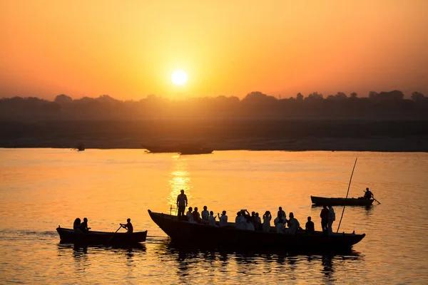 Ganj nehrinde tekne ile Hacı siluetleri ile şafak. Varanasi, Hindistan.