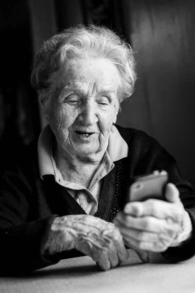 高齢者女性のスマート フォンで入力 — ストック写真