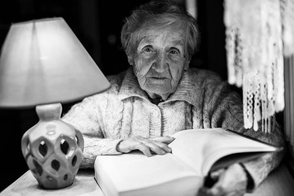 Yaşlı Kadın Geceleri Bir Masa Lambası Altında Bir Kitap Okur — Stok fotoğraf