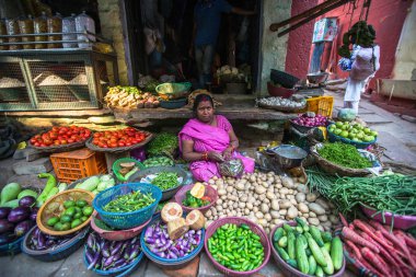 VARANASI, INDIA - MAR 21, 2018: Street seller of greenery and vegetables. According to legends, the city was founded by God Shiva about 5000 years ago. clipart
