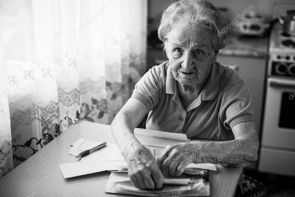Elderly woman pensioner with bills to pay utilities.