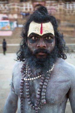 VARANASI, INDIA - MAR 17, 2018: Sadhu (holy man) on the ghats of Ganga river. Varanasi is most important pilgrimage sites in India, one of the 7 sacred cities of Hinduism.  clipart