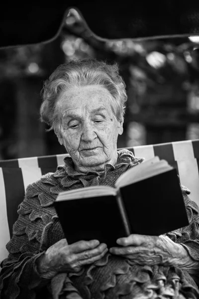 Yaşlı Kadın Bir Hamakta Oturmuş Bir Kitap Okuma — Stok fotoğraf