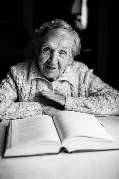 Пожилая Женщина Читает Книгу Сидя Столом — стоковое фото