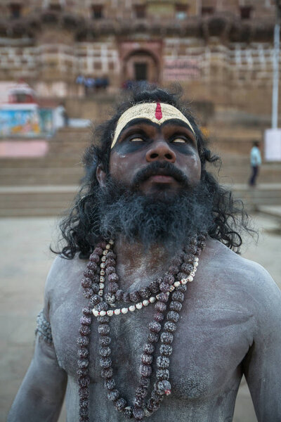 VARANASI, INDIA - MAR 17, 2018: Sadhu (holy man) on the ghats of Ganga river. Varanasi is most important pilgrimage sites in India, one of the 7 sacred cities of Hinduism. 