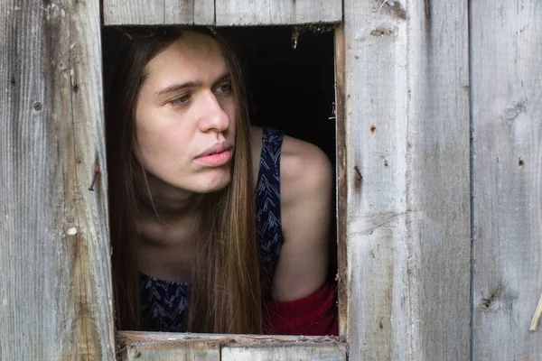 Junge Frau Mit Langen Haaren Blickt Aus Den Holzschuppenfenstern — Stockfoto