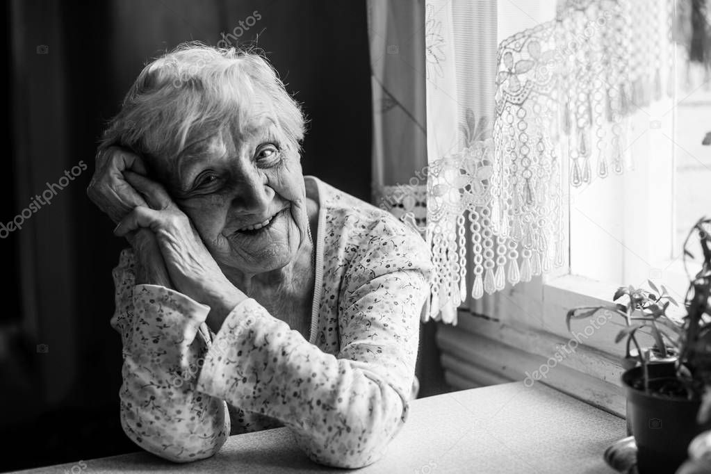 Black and white portrait of an elderly positive woman 75-80 years old.