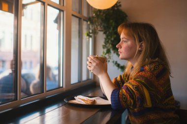 Pencerenin yakınındaki bir kafede oturan kız.