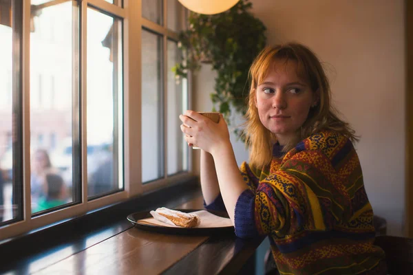 Pencerenin yakınındaki bir kafede oturan kız.