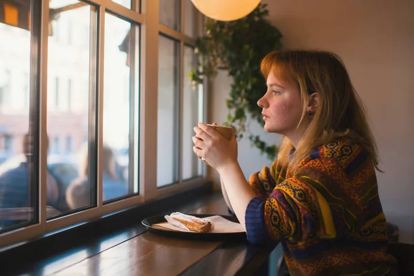 Pencerenin yakınındaki bir kafede oturan kız.