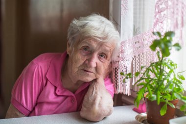 Evde masada oturan yaşlı kadın.