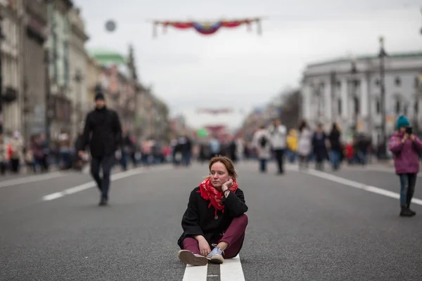 にぎやかな通りの途中で道路に座っているかわいい女の子 — ストック写真