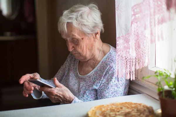 Yaşlı Kadın Bir Smartphone Ile Onun Elinde Oturur — Stok fotoğraf