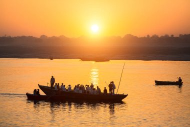 Teknelerin siluetleri ile muhteşem gün batımı sırasında hacıların kutsal Ganj Nehri, Varanasi, Hindistan.