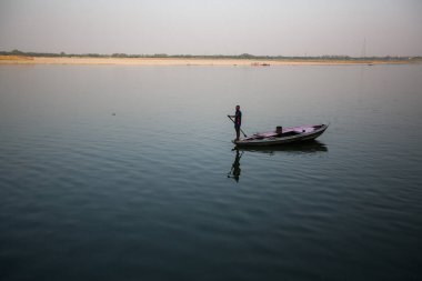 Varanasi, Hindistan - 26 Mar 2018: Bir teknede Boatmen Varanasi kıyı boyunca Ganj Nehri üzerinde suyun içinden süzülüyor. Efsaneye göre şehrin yaklaşık 5000 yıl önce Tanrı Shiva tarafından kuruldu