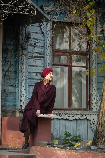 Blondýnka Burgundském Kabátě Baretu Sedící Verandě Starého Dřevěného Domu — Stock fotografie