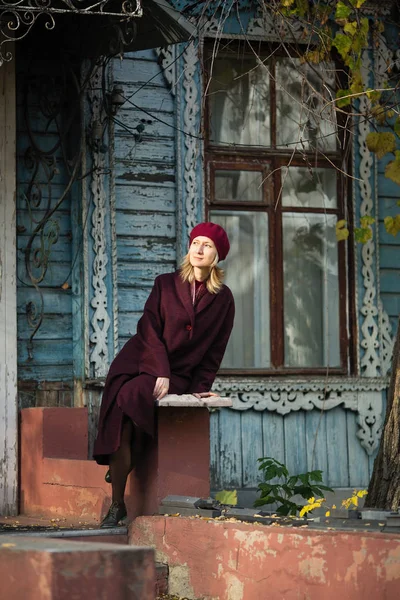 Blondýnka Burgundském Kabátě Baretu Sedící Verandě Starého Dřevěného Domu — Stock fotografie