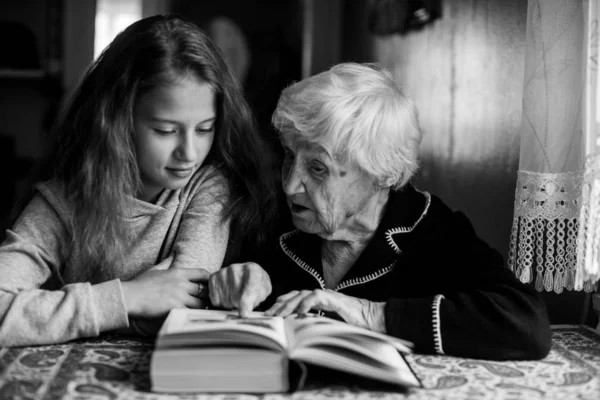 A granny with a little girl reading a book. Black and white photography.