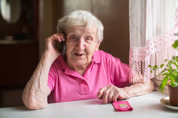Ηλικιωμένη Γυναίκα Μιλάει Στο Τηλέφωνο Κάθεται Στο Τραπέζι — Φωτογραφία Αρχείου