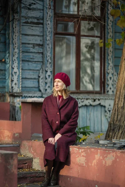 Eski Ahşap Evin Verandasında Oturan Bordo Paltolu Kadın — Stok fotoğraf
