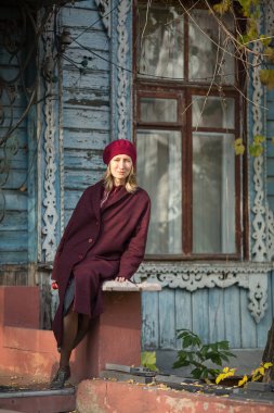 Sonbaharda eski bir ahşap evin yanında ceketli bir kadın..