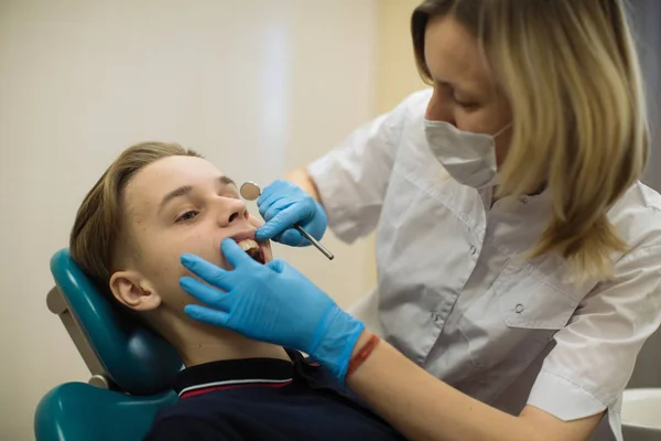 歯医者は診療所の歯科医の椅子で男の子の歯の検査をしている ヘルスケアと生活習慣医学の概念 — ストック写真