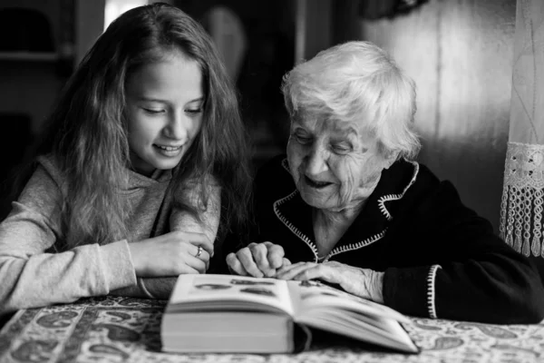 一个少女和他的祖母一起看书 黑白照片 — 图库照片