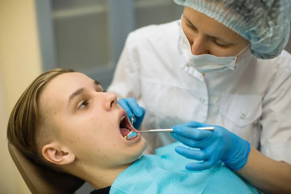 歯医者は診療所の歯科医の椅子で人の歯を検査する 血液学医学の概念 — ストック写真