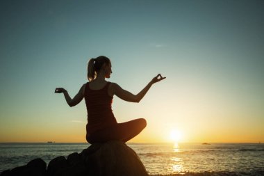 Yoga silueti genç bayan gün batımında denizde.