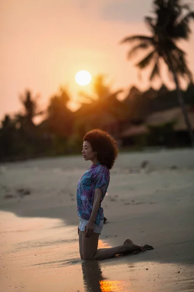 若いですアジアの女性ひざまずいていますサーフライン上の海のビーチで素晴らしい夕日 — ストック写真