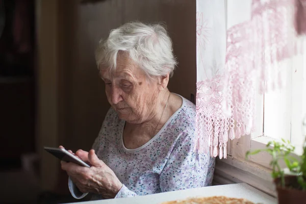 Oude Vrouw Zit Met Een Smartphone Haar Handen Kamer — Stockfoto