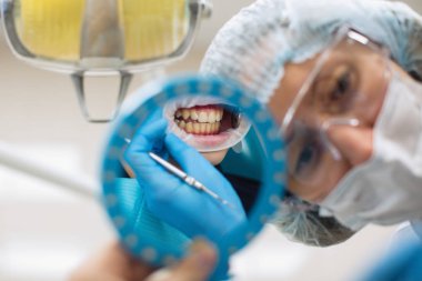 Ayna ağzında ve dişlerinde yansıma, dişçi kadın diş muayenesi yapıyor.. 