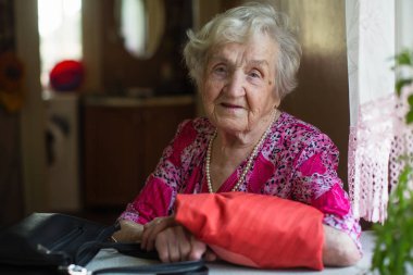 Masada el çantasıyla yaşlı kadın portresi.