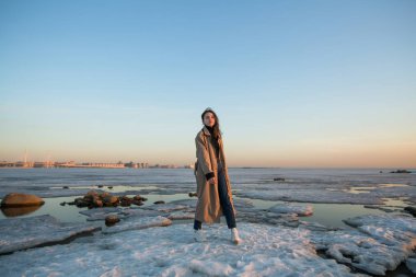Fotoğraf, kışın St. Petersburg 'da Finlandiya Körfezi kıyısında genç bir kadını çekiyor..