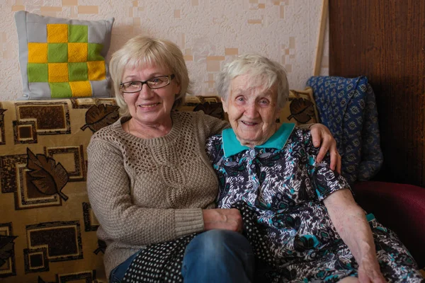 一个老年妇女和她的成年女儿依偎在沙发上 — 图库照片
