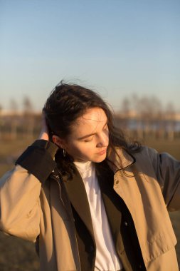 Dışarıda kameraya poz veren alımlı genç bir kadın..