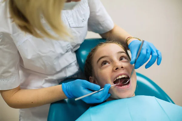歯医者は診療所で女の子の歯の検査を行う — ストック写真