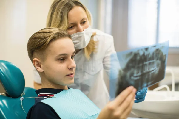 歯科医院で顎をX線治療を受けた少年に示す歯科医 — ストック写真
