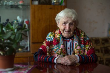 Masada oturan parlak elbiseli yaşlı bir kadın..